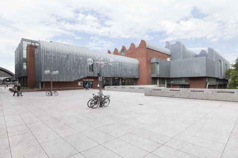 Blick auf das Museum mit seinen roten Ziegeln, der silbernen Fassade und der charakteristischen wellenkammartigen Form.