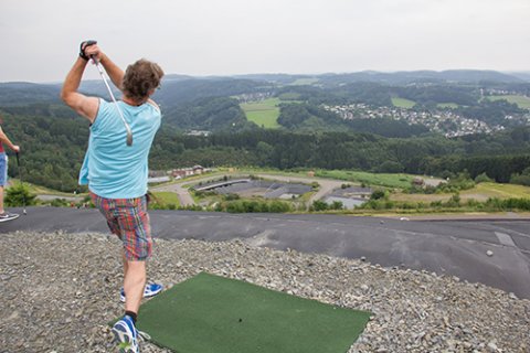 Ein junger Mann beim Golfspielen mit Ausblick ins Bergische Land. 