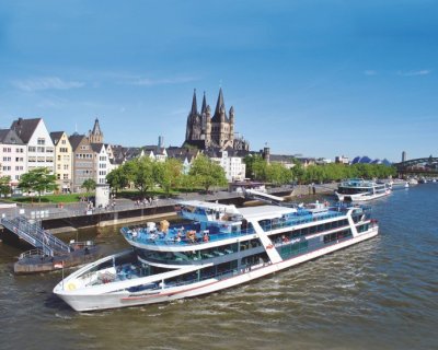 Ein Ausflugsschiff der Köln-Düsseldorfer liegt vor dem Kölner-Altstadtpanorama mit Groß St. Martin und Dom.